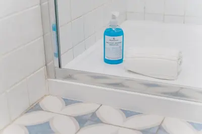 a blue bottle of soap sitting on a shelf in a bathroom mirror at GuestReady - Almada 516 in Porto