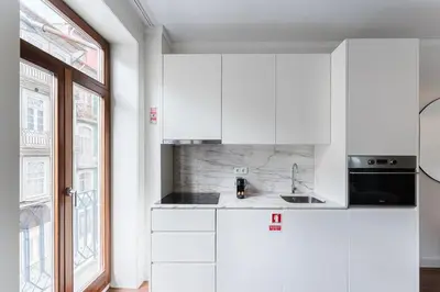 a white kitchen with a sink and a window at GuestReady - Almada 516 in Porto