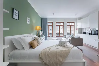 a bedroom with a large white bed and a kitchen at GuestReady - Almada 516 in Porto