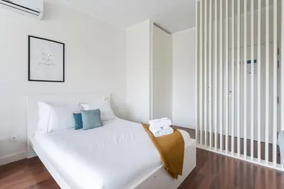 a white bedroom with a white bed with blue pillows at GuestReady - Almada 516 in Porto