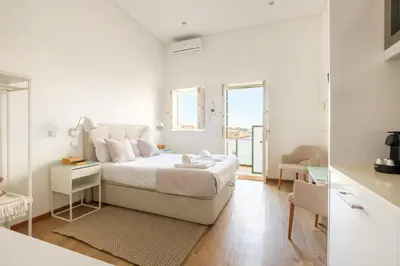 a white bedroom with a bed and a mirror at GuestReady - Port Studio 4 in Vila Nova de Gaia