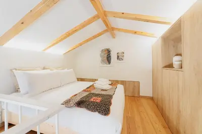 a bedroom with a white bed in a room with wooden ceilings at Ribeira Charming Apartment in Porto
