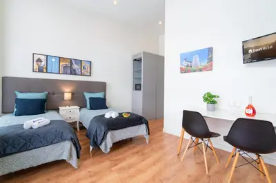 a bedroom with two beds and a desk and chairs at Host Wise - Sweet Bright Flats - City Center in Porto