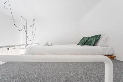 a white bed with two green pillows on it at GuestReady - Cosy in the Historic Heart of Porto in Porto