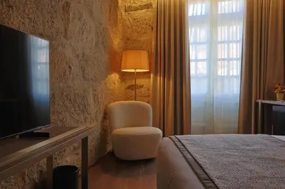 a hotel room with a bed and a chair and a television at Timbre Virtudes in Porto