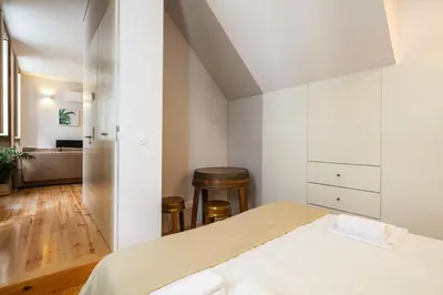a bedroom with a bed with white walls and wooden floors at Charming T2 by Indulge Porto Flats in Porto