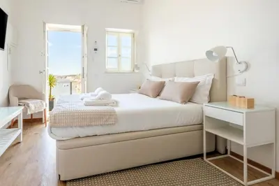 a white bedroom with a bed and a table at GuestReady - Port Studio 3 in Vila Nova de Gaia