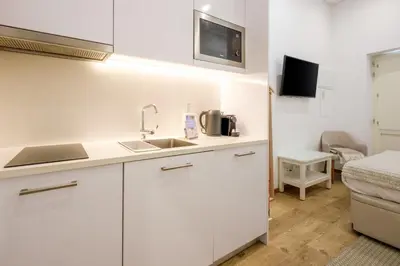 a kitchen with white cabinets and a sink and a bed at GuestReady - Port Studio 3 in Vila Nova de Gaia