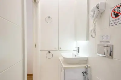 a white bathroom with a sink and a phone at GuestReady - Port Studio 3 in Vila Nova de Gaia