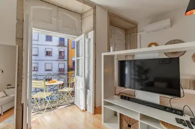a living room with a large television and a balcony at Virtudes Flat w/ AC & Balcony by LovelyStay in Porto