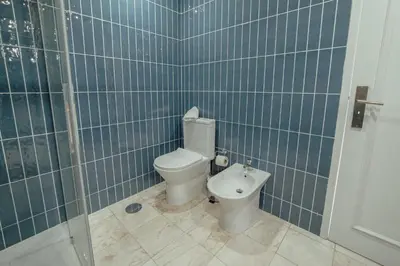a blue tiled bathroom with a toilet and a shower at Grand Premium Boavista Apartment by Vacationy in Porto