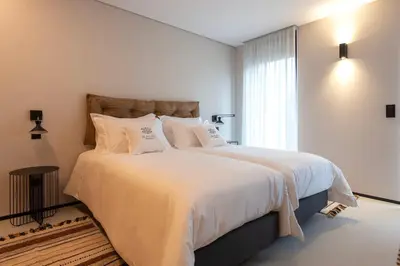 a bedroom with a large bed with white sheets and a window at Blau 1911 in Porto