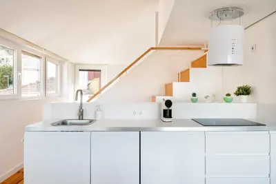 a white kitchen with white cabinets and a staircase at Casa Flora in Porto