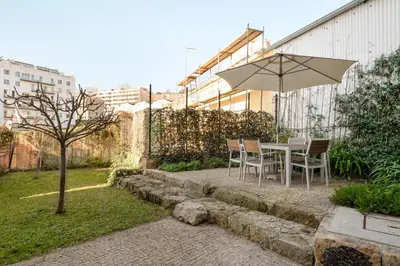 a table and chairs with an umbrella in a garden at Casa Flora in Porto