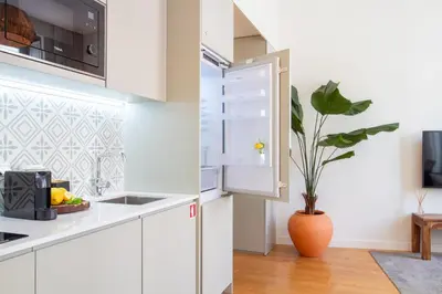 a kitchen with white cabinets and a plant in a vase at Mouzinho da Silveira 215 by LovelyStay in Porto