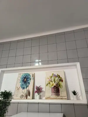 a shelf with three pictures and flowers on it at Ap Centro de Gaia in Vila Nova de Gaia