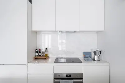 a white kitchen with white cabinets and a sink at GuestReady - The Modern Silveira in Porto