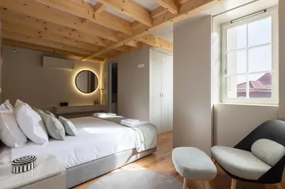 a bedroom with a large bed and a chair at ORM Portas Santa Catarina Apartments in Porto