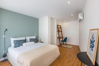 a bedroom with a large white bed and a blue chair at Pestana Apartments - Premium in Porto