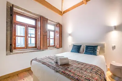 a bedroom with a large white bed with blue pillows at GuestReady - Miragaia Stone Studios & Apartments in Porto