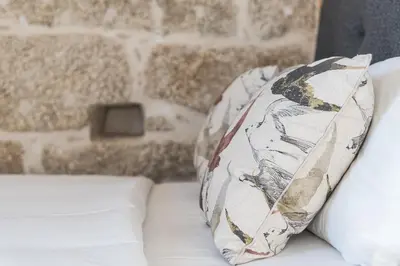 a pillow sitting on a couch with a brick wall at GuestReady - Miragaia Stone Studios & Apartments in Porto