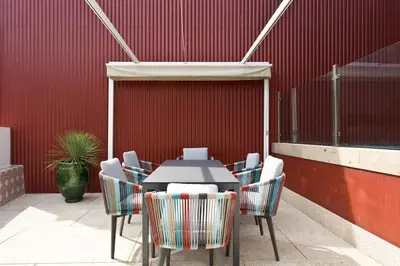 a table and chairs in front of a red wall at BOUTIQUE Rentals- P*O*R*T*O Ribeira in Porto