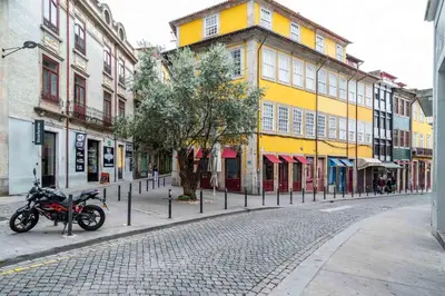 a motorcycle parked on a cobblestone street with buildings at Limehome Porto Rua Das Oliveiras in Porto