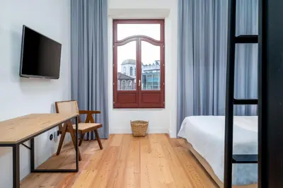 a bedroom with a bed and a desk and a window at Limehome Porto Rua Das Oliveiras in Porto