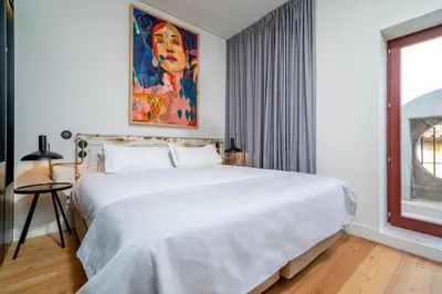 a bedroom with a large white bed with a painting on the wall at Limehome Porto Rua Das Oliveiras in Porto