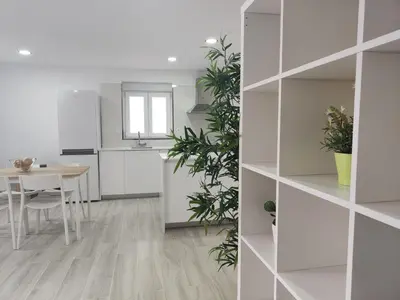 a kitchen and dining room with white cabinets and a table at Casa Mini-Ventuzelo by JC in Porto