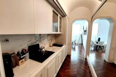 a kitchen with white cabinets and a dining room with a table at Dream on - Clérigos Tower in Porto