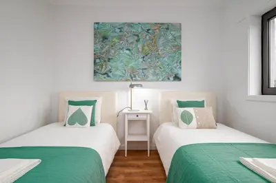 two twin beds in a room with a painting on the wall at Lovely 2BR w/ views over the river, parking incl in Vila Nova de Gaia