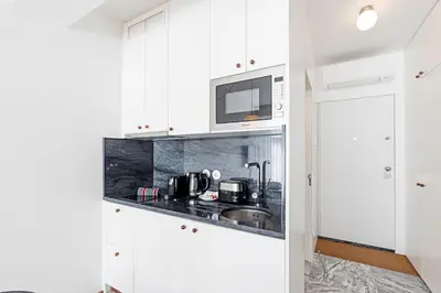 a white kitchen with a sink and a microwave at Ceuta Studio Apartments by LovelyStay in Porto