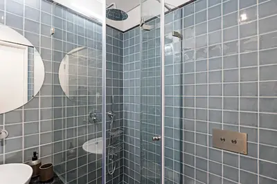 a blue tiled bathroom with a shower and a sink at Ceuta Studio Apartments by LovelyStay in Porto