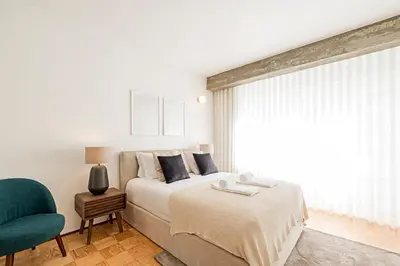 a bedroom with a bed and a chair and a window at Ceuta Studio Apartments by LovelyStay in Porto