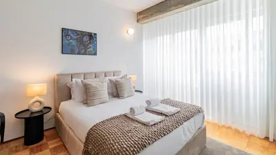 a white bedroom with a bed with towels on it at Ceuta Studio Apartments by LovelyStay in Porto