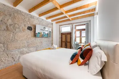 a bedroom with a white bed and a stone wall at GuestReady - Miragaia Stone Studios & Apartments in Porto