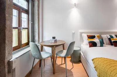 a bedroom with a bed and a table and chairs at GuestReady - Miragaia Stone Studios & Apartments in Porto