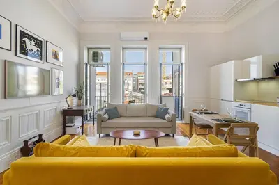 a living room with a yellow couch and a kitchen at Stylish Downtown Apartment in Porto