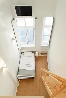 a attic room with a bed and two windows at PORTO CONCEPT HOME - Campo Alegre in Porto
