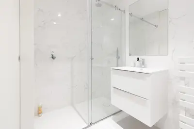a white bathroom with a shower and a sink at Dragão - Indigo Antas Park in Porto