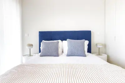a bedroom with a large bed with blue headboard and pillows at Dragão - Indigo Antas Park in Porto