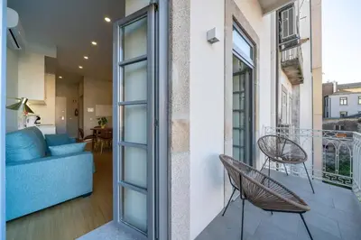 a room with a balcony with a blue couch and chairs at 31 de Janeiro Flat by Amber Star Rent in Porto